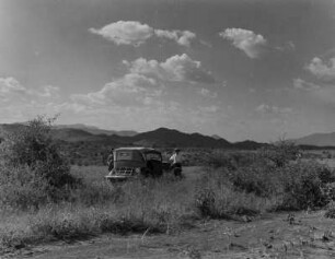 Anseba-Graben : Blick auf die den Anseba-Graben begrenzenden Berge nördlich von Keren. In der Bildmitte ein Auto, davor ein Mann (vielleicht Carl Troll oder Rudolf Schottenloher)