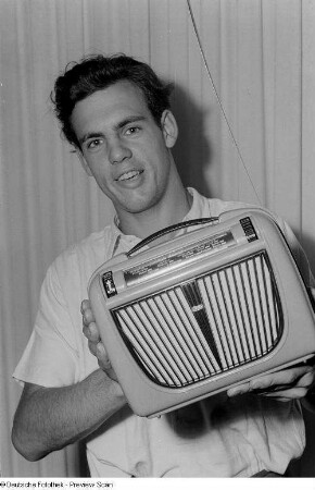 Ein Mann präsentiert den Radioempfänger RFT-Koffersuper 6 D 71 der Rundfunk- und Fernmeldetechnik (RFT) des VEB Fernmeldewerk Leipzig, Herbstmesse 1953