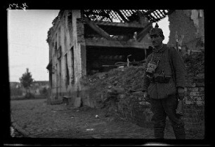 Nicht identifizierbare Ortschaft bei Aubers (Dep. Nord, Frankreich), Saint-Quentin (Dep. Aisne, Frankreich) oder "Le Mesnil-en-Vespres" (nicht lokalisierbar, Frankreich): Soldat mit Pickelhaube (darauf die Zahl "17") und umgehängtem Gewehr vor einer Gebäuderuine (Nahaufnahme)