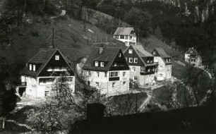 Rathen-Niederrathen. Siedlungshäuser und Pensionen am Amselgrund. Blick über den Grünbach zum Basteiweg