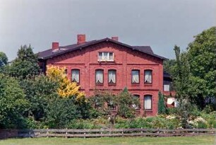 Dorfstraße (34): Bauernhaus aus Backstein: Giebelseite Wohntrakt: Vorgarten, Holzzaun