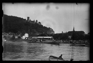 Blick von Kreuzwertheim über den Main auf eine Menschenmenge am Mainufer, geschmücktes Schiff mit der Aufschrift "Sängerschiff Wertheim", Lagerhaus und Burg