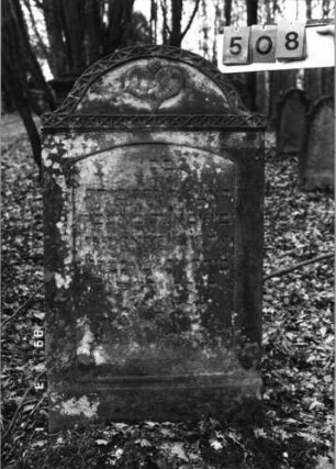 Grabstein 508 (Index: 99752930) Material: Sandstein Zustand: stark verwittert mit Textverlust Maße HxBxT: 118x67x17 cm Beschreibung: Stele, eingezog. Segmentbogenabschl. , Schriftfeld eingetieft mit Segmentbogenabschl Symbolik: Herz, geometrisches Fries: Grabstein 508