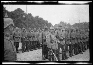 Nicht identifizierbare Ortschaft in Nordfrankreich oder Belgien: Soldaten mit Pickelhaube in Aufstellung auf einer breiten gepflasterten Parkstraße, davor ein Offizier zu Pferd (Nahaufnahme)