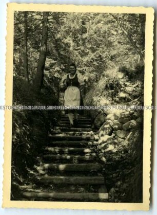 Frau im Dirndl auf einem Waldweg