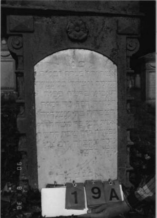 Grabstein 19 Material: Stein Zustand: leichte Verwitterungsspuren Maße HxBxT: 190x51x29 cm Beschreibung: Reihengrab, Vorderseite hebräische Inschrift, Rückseite deutsche Inschrift Symbolik: fünfblättrige Blüte Besonderheit: --: Grabstein 19 A