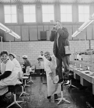 Köhra. Fotograf im Kartoffelhaus : Köhra. Ein Fotograf steht auf einem Stuhl in einer Kartoffel-Reinigungshalle. Eine Arbeiterin hält den Stuhl