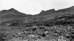 Vulkanlandschaft : Blick auf einen Hang mit Lavablöcken. Im Hintergrund Vulkane.