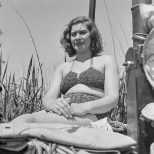 Frau im Bikini sitzt auf einem Segelboot