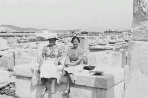 Reisefotos Griechenland. Delos (Stadt). Touristinnen beim Besichtigen der antiken Ruinen, auf Trümmern sitzend