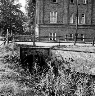 Hoherdammer Mühle: Rentnerwohnheim der Gemeinde: Durchlauf der Norderbeste: darüber Weg mit Geländer: hinten links Bäume: vorn Schilf