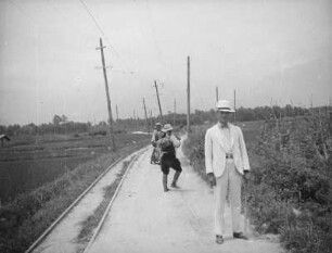 Neulandgewinnung in der Bucht von Tokio : Neulandgewinnung in der Bucht von Tokio. Urbarmachung durch Bepflanzung. Feldweg mit zwei Japanern und einem Europäer. Ansicht mit Strommasten