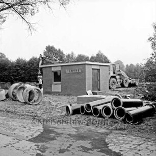 Abwasser: Bünningstedter Straße: Pumpstation: Rohbau: rechts und links davor Rohre unterschiedlicher Größe: hinten rechts Bagger: hinten links zwei Arbeiter vor zweitem Bagger: hinten Bäume