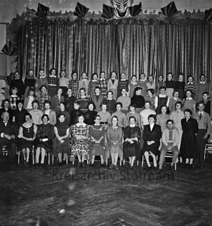 Oldesloer Jugendchor: Hotel Oldesloer Hof: Saal: vor Bühne: Probe für Faschingsveranstaltung: Gruppenaufnahme mit Musikdirektor August König
