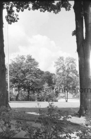 Kurpark: Blick von Hauptgebäude der Kreisverwaltung [später Gebäude A] Richtung Sülzberg und Bangertstraße: vorn Rosensträucher, rechts und links Bäume, links Fahnenmast: hinten Grünanlage