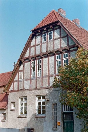 ehemaliges Gut Trenthorst-Wulmenau: Zentrale: Wulmenau 6: traufständiges Mehrfamilienwohnhaus: südliche Giebelseite mit Eingangstür, Giebel mit Fachwerk und Vorkragungen: links rückwärtiger Querbau [angeschnitten]