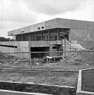 Sporthalle: Schulzentrum Glinde: Oher Weg: Rohbau: vorn Bauzaun: dahinter Sand- und Erdhaufen und Baumaterial: hinten Mitte Arbeiter auf Gerüst