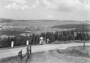 Blick auf Plešivec : Blick über eine bewaldete Landschaft auf Plešivec. Eine Frau und ein Mann auf einer Straße im Vordergrund
