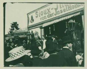 Zuschauer vor einer Schaubude mit "Sioux-Indianern" mit Karussell und Riesenrad II