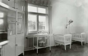 Säuglingsheim. Krankenzimmer mit Instrumentenschrank, Beistelltisch und Gitterbetten für Kleinstkinder