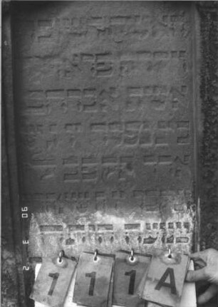 Grabstein 111 (Index: 99608795) Material: Sandstein Zustand: leicht verwittert Maße HxBxT: 135x63x18 cm Beschreibung: Stele mit geschwungenem Rundbogen, vertiefter Textteil in gleicher Form Besonderheit: BIN (?): Grabstein 111A