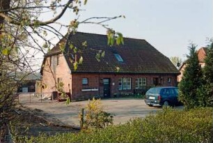 Blumendorf 1: traufständige Doppelkate aus Backstein: Straßenfront: Eingangstüren, Hausnummer, Sprossenfenster: Giebelseite, oben Luke: vorne Vorplatz, Auto: links Einfahrtor, hinten Schuppen: 22. April 2003