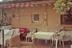 Wiesenstraße 37: Reetdachhaus mit Umbauten: Traufseite, Teilansicht: Veranda, Markise, Gartenmöbel