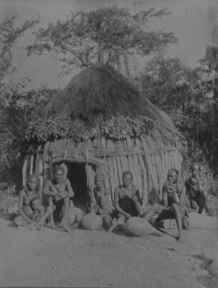 Gruppenbildnis : Gruppenportrait mit Männern und Frauen vor einer Hütte