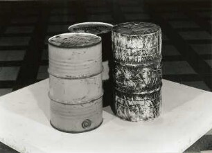 Three oil barrels, one wrapped (Drei Ölfässer, eines verpackt)