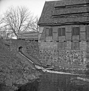 Drahtmühle: Restaurierung: vorn Mühlenbach: links Brücke mit Wehr: oben links Stapel mit Brettern: dahinter Baum