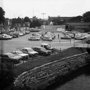 Parkplatz Heiligengeiststraße: parkende Pkw, vorne die Trave, mittig verläuft die Heiligengeiststraße, Blick Richtung Osten