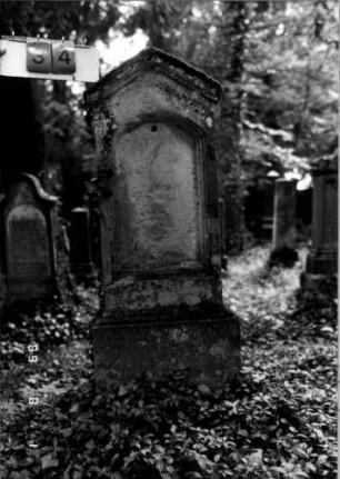 Grabstein 34 (Index: 100109256) Material: Sandstein Zustand: völlig verwittert, Schriftplatte fehlt Maße HxBxT: 138x52x18 cm Beschreibung: Stele, Sockel, giebelartiger Abschluß, Schriftfeld mit Segmentbogen: Grabstein 34