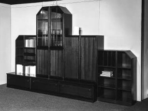 Anbauwand : Dresden-Hellerau. VEB Deutsche Werkstätten Hellerau. Hausmesse, 1986. Anbauwand. Holz, folienbeschichtet in Mahagonioptik, dunkel (1986; VEB Deutsche Werkstätten Hellerau)