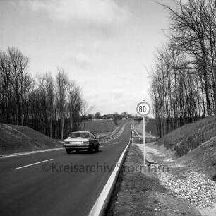 Landesstraße zwischen Bad Oldesloe und Bad Segeberg: Ausbaustrecke: rechts Verkehrsschild: links Pkw: rechts und links Erdwälle mit Baumbestand