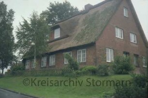Backsteinhaus mit Reetdach: ehemalige Schule: traufständige Straßenfront: Giebelseite