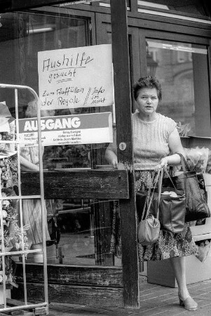 Ex-DDR Bürger in westdeutschen grenznahen Städten, 8. + 9. August 1990. hier: Eingangstür vom PLUS-Markt in Helmstedt, Frau mit drei Handtaschen