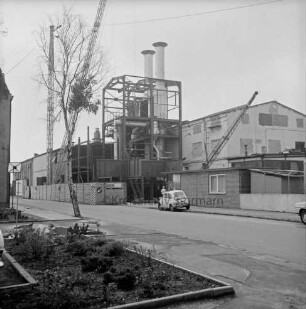 Gießtechnik Nord GmbH: Kampstraße: Eisengießerei: [Fabrikkomplex ehemals Eisengießerei Kampnagel AG]: Außenaufnahme Werksanlagen von Straße aus: Kupol-Schmelzöfen in Bau, Bauzaun, Baukräne: vorne Straße, parkende Autos, Grünfläche