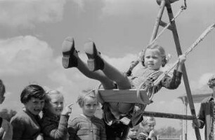 Ein schaukelndes Mädchen und wartende Kinder
