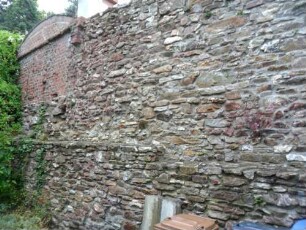 Kirchhofmauer im Westen mit Mauersteinverband im Verlauf nach Westnordwesten über Feldseite (mit ehemaligem Grabenbereich)
