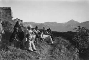 Männer der Kabylen : Eine Gruppe Männer der Kabylen sitzt vor dem Dorf, vor ihnen ein junger Feigenbaum.