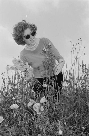 Renate Rössing in einer Wiese beim Pflücken eines Blumenstraußes