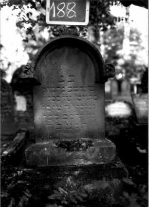 Grabstein 188 (Index: 100109691) Material: Sandstein Zustand: verwittert Maße HxBxT: 112x57x22 cm Beschreibung: Stele, getreppter Sockel, überstehender eingezogener Rundbogenabschluß mit Verdachung und Mittel- und Eckakroteren Symbolik: stilisierte Blätter in den Akroteren Besonderheit: Kindergrab: Grabstein 188