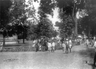 Buitenzorg (Bogor), Java/Indonesien. Spazierenden Einheimische mit Kindern auf einer Parkallee, am Wegesrand Verkäufer mit Warenständen