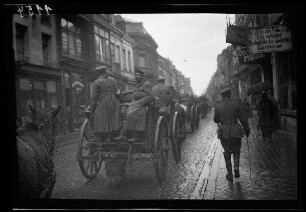 Nicht identifizierbare Ortschaft bei Saint-Amand (=Saint-Amand-les-Eaux (?)), Douai, Cambrai (alle Dep. Nord, Frankreich) oder bei Maisnières (Dep. Somme, Frankreich): Pferdewagenkolonne auf einer gepflasterten Ortsstraße (Rückansicht)