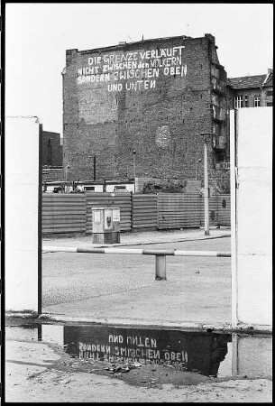 Brandmauer mit Inschrift "Die Grenze verläuft nicht zwischen den Völkern / sondern zwischen oben und unten"