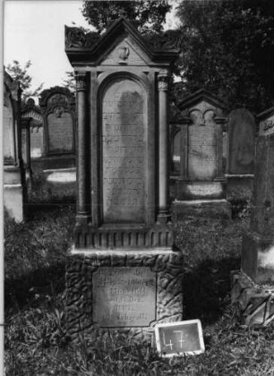 Grabstein 47 (Index: 99801848) Material: Sandstein Zustand: leicht verwittert Maße HxBxT: 183x47x29 cm Beschreibung: ädikulaartige Stele mit Säulen, Sockel rusticaartig, giebelartiger Abschluß mit Verdachung und Akroteren, eingetieftes Schriftfeld mit Rundbogen Symbolik: Levitenkanne: Grabstein 47
