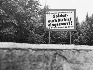Berliner Mauer am Brandenburger Tor : Blick über die Staatsgrenze zu Westberlin mit einem Plakat "Soldat, auch Du bist eingesperrt!" vom Brandenburger Tor