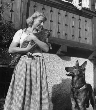Junge Frau mit Schäferhund, eine Katze auf dem Arm haltend