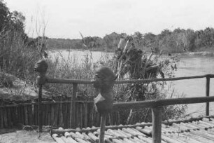 Mawesi-Fluss bei Tunduru mit Köpfen : Landschaft mit einer Brücke über einen Fluss. An dem Geländer der Brücke sind Tonköpfe