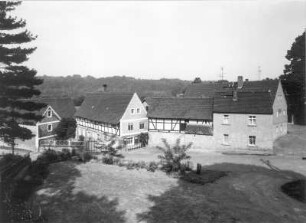 Höfgen (Grimma-Höfgen). Ortsteilansicht mit Fachwerkhäusern. Blick vom Platz vor der Pfarrkirche nach Westen